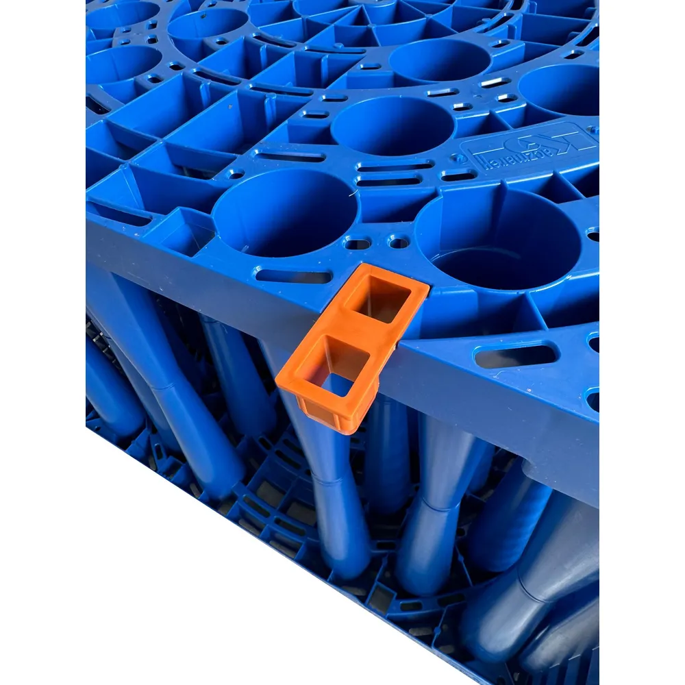 Närbild av en blå Teleskoprör 315 (höjd: 400 mm, för lättbetäckning) med ett industriellt plastgaller med cylindriska öppningar och en orange rektangulär klämma på kanten.