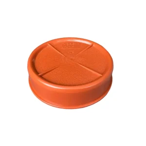 Ett runt, orange plastlock kallat PP Lock , med strukturerad yta och lätt upphöjd kant, tillverkat av hållbart PP-material, mot en vit bakgrund.