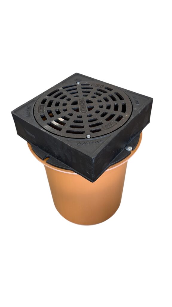 Ett fyrkantigt avloppsgaller i svart metall är monterat ovanpå en rund, orange plastbehållare mot en vit bakgrund.