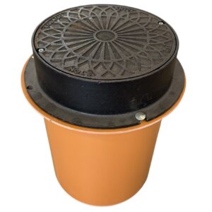 Ett litet svart dekorativt brunnslock placerat ovanpå en orange växtkruka mot en vit bakgrund.