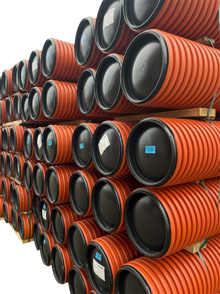 Dagvattenbrunn 400 - 2 meter: Flera orangefärgade, räfflade plaströr med svarta tätade ändar är horisontellt placerade på träpallar, vissa med etiketter och streckkoder, allt mot en vit bakgrund.