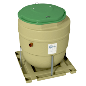 En beige cylinderformad tank med grönt lock, märkt "Baga slamavskiljare 9m3 - 7-10 hushåll", vilar på en fyrkantig pall med metallstöd mot en vit bakgrund.