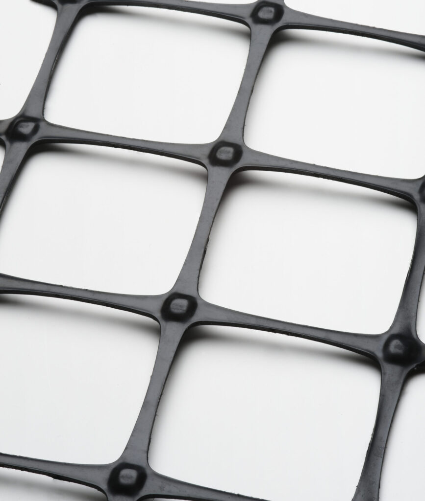 En närbild av Geonät PP 30/30L svart plastgaller med kvadratiska öppningar, diagonalt placerade på en vit bakgrund.
