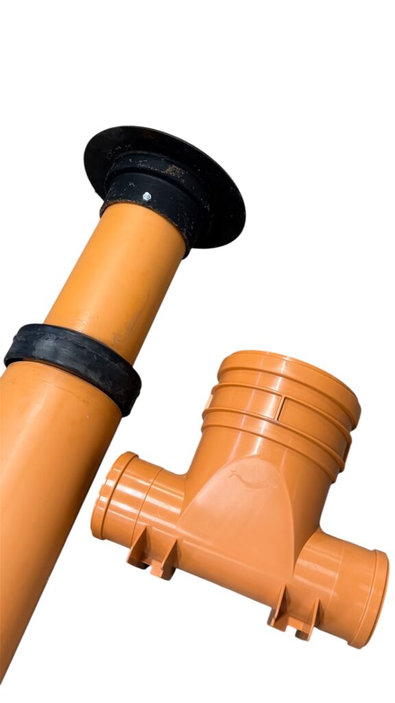 Två orangefärgade PVC-rör med svarta gummikopplingar visas mot en vit bakgrund. Det ena röret är vertikalt, medan det andra är en T-formad koppling som ligger horisontellt.