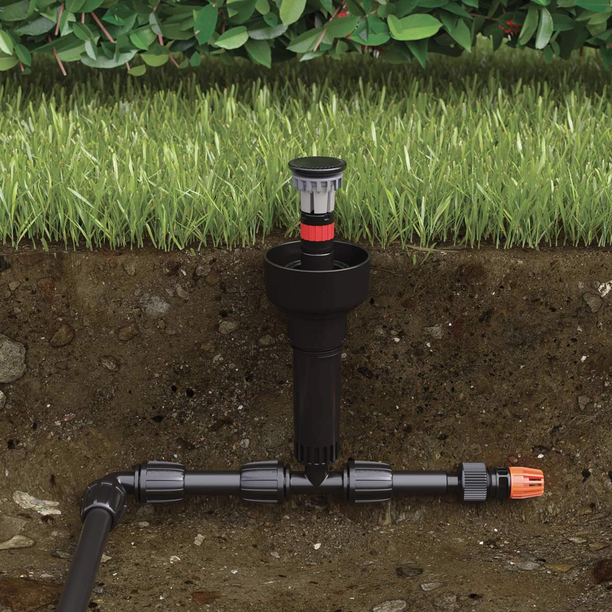 En tvärsnittsbild av ett sprinklersystem visar underjordiska rör som är anslutna till ett Claber Colibri-mikrosprinklerhuvud (90° pop-up), med gräs och buskar ovanför markytan.